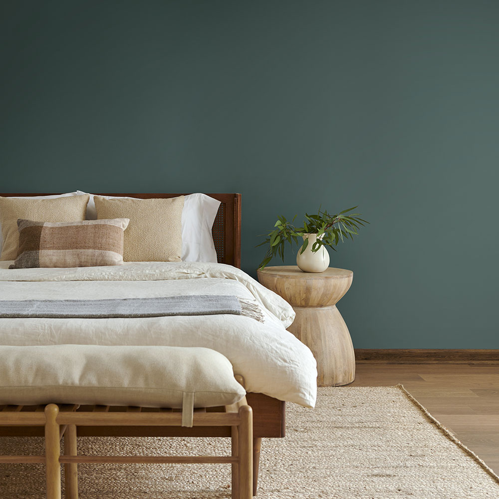 a minimal bedroom showing the wall behind the bed painted in behr hidden gem deep turquoise green